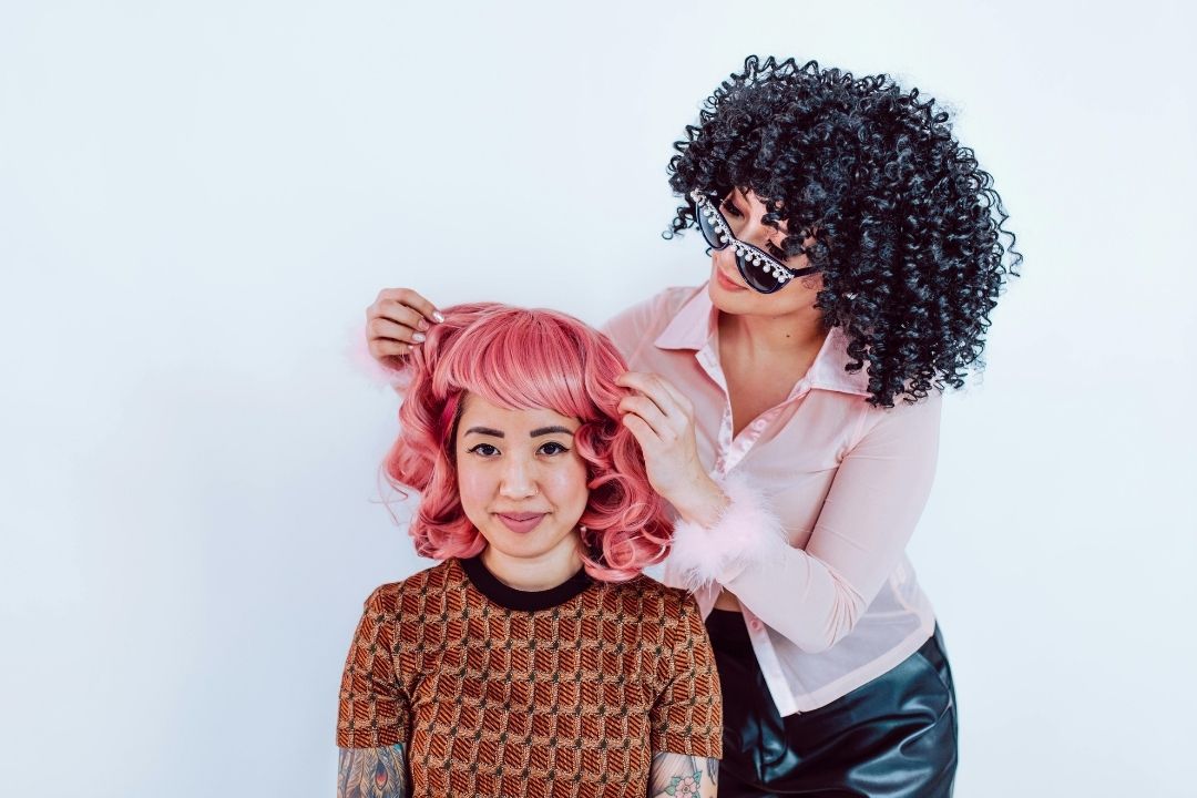 a woman installing a wig for another woman